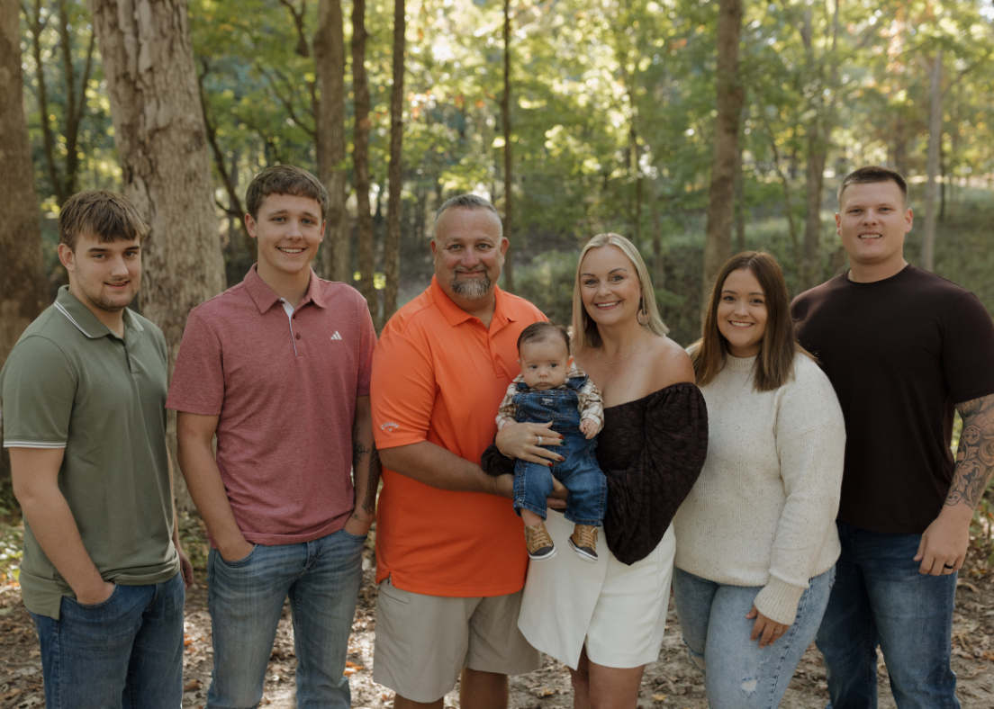 Brandy's family of seven standing outdoors in a forested area